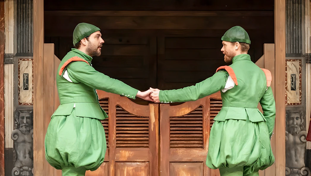 Actors in green costumes performing "The Comedy of Errors" on stage.