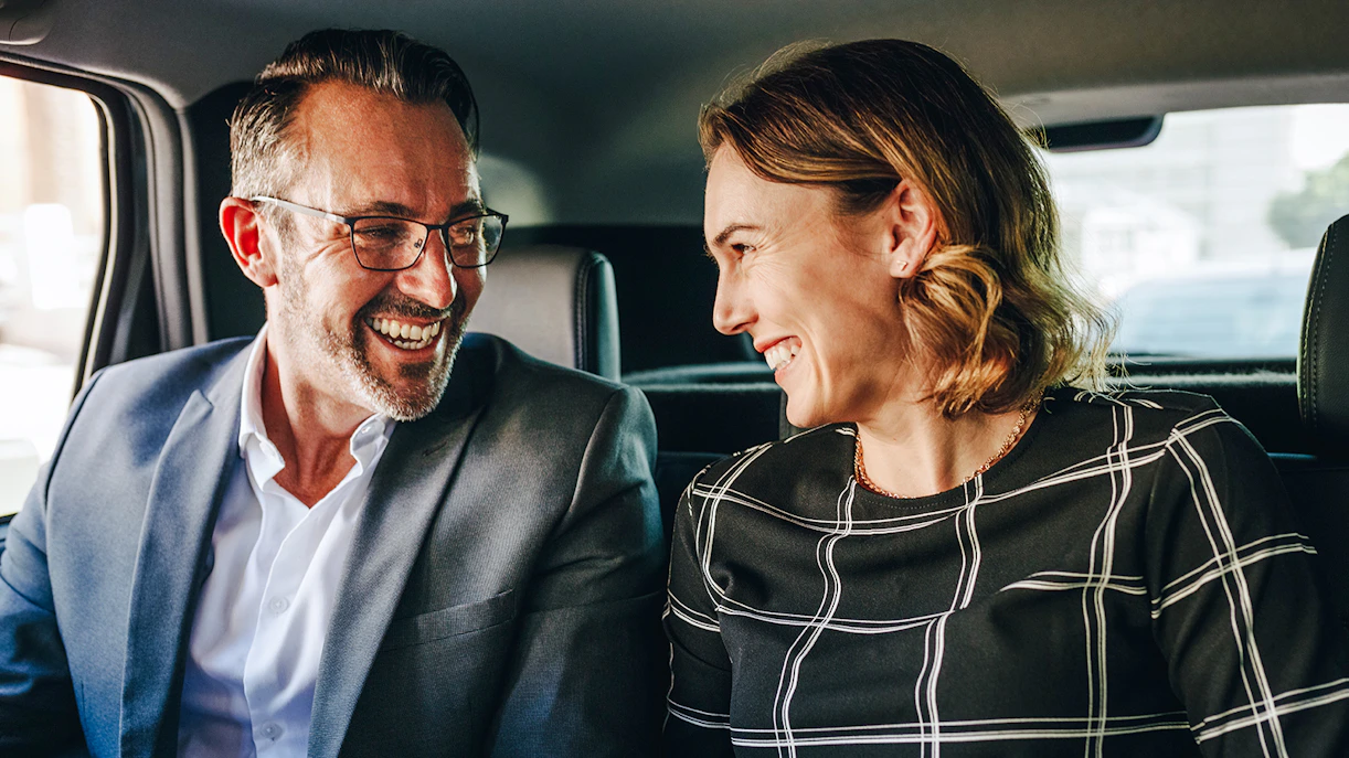 Couple smiling in backseat during private airport transfer.