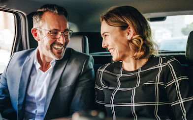 Couple smiling in backseat during private airport transfer.