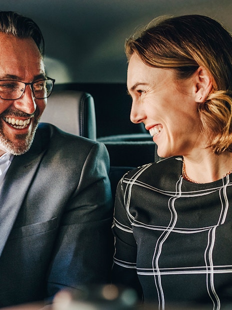 Couple smiling in backseat during private airport transfer.