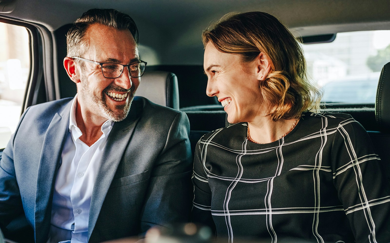 Couple smiling in backseat during private airport transfer.