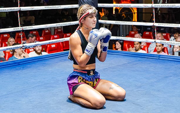 Muay Thai fighter kneeling in Patong Boxing Stadium ring, Phuket.