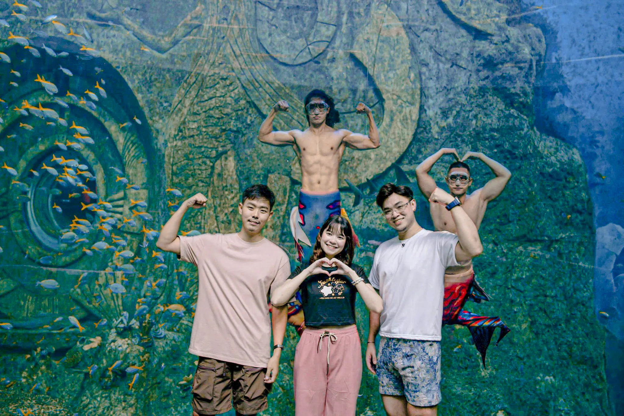 Group posing with performers in mermaid costumes at Phu Quoc VinWonders aquarium.