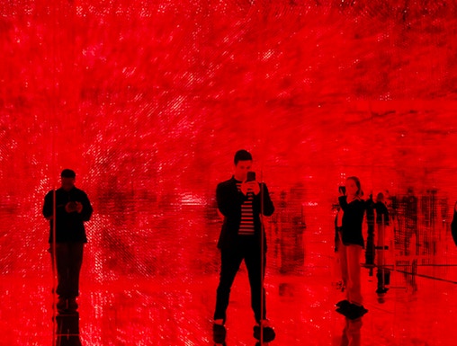 Visitors in a red-lit room at Mercer Labs: Museum Of Art & Technology exhibit.