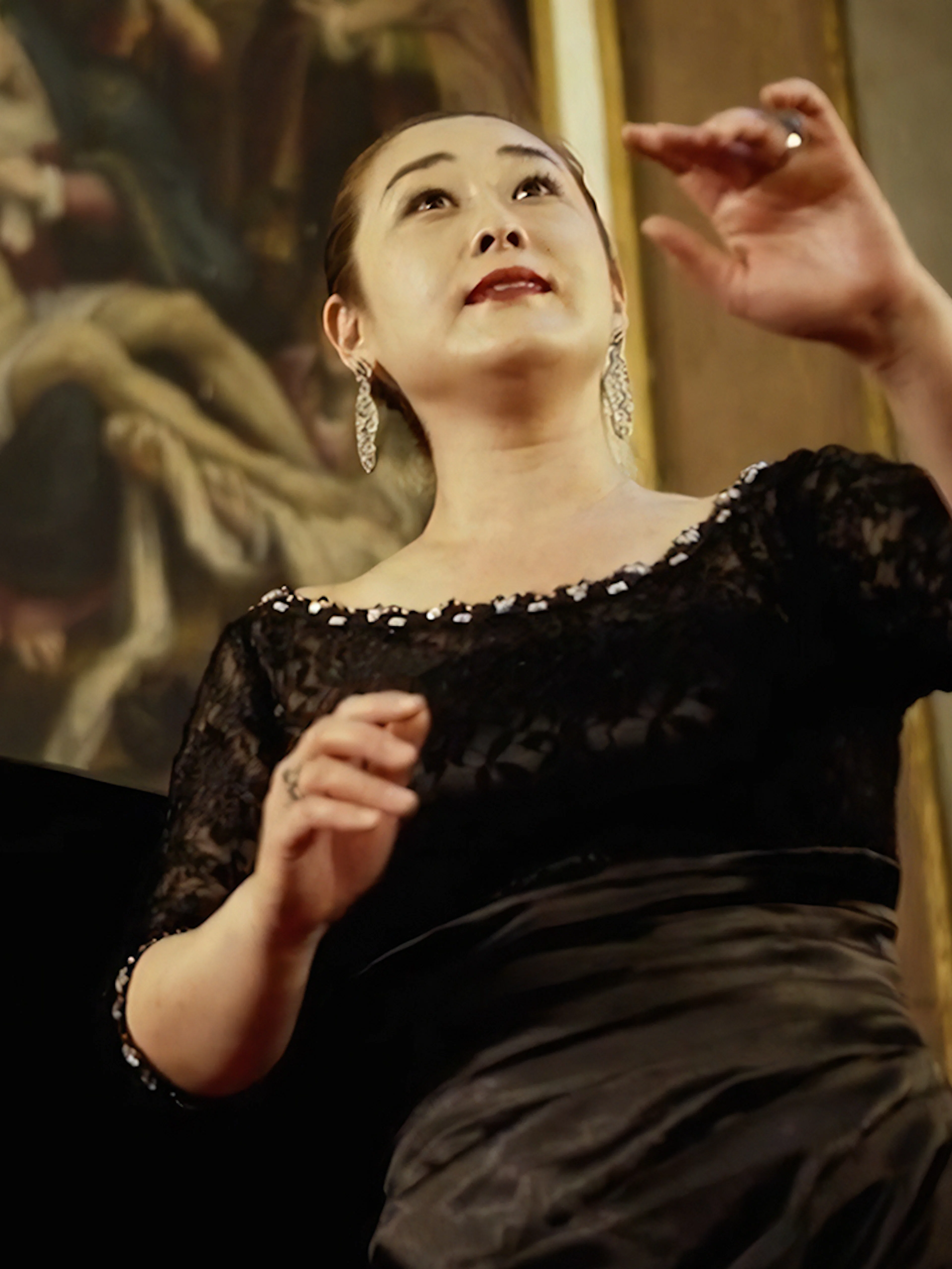 Opera singer performing at a concert in Florence with classical painting in the background.