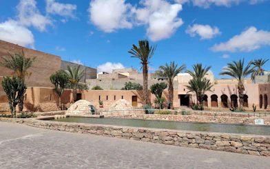 Agadir desert courtyard with palm trees and traditional Berber architecture.