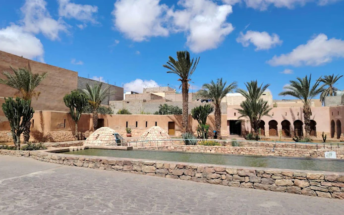 Agadir desert courtyard with palm trees and traditional Berber architecture.