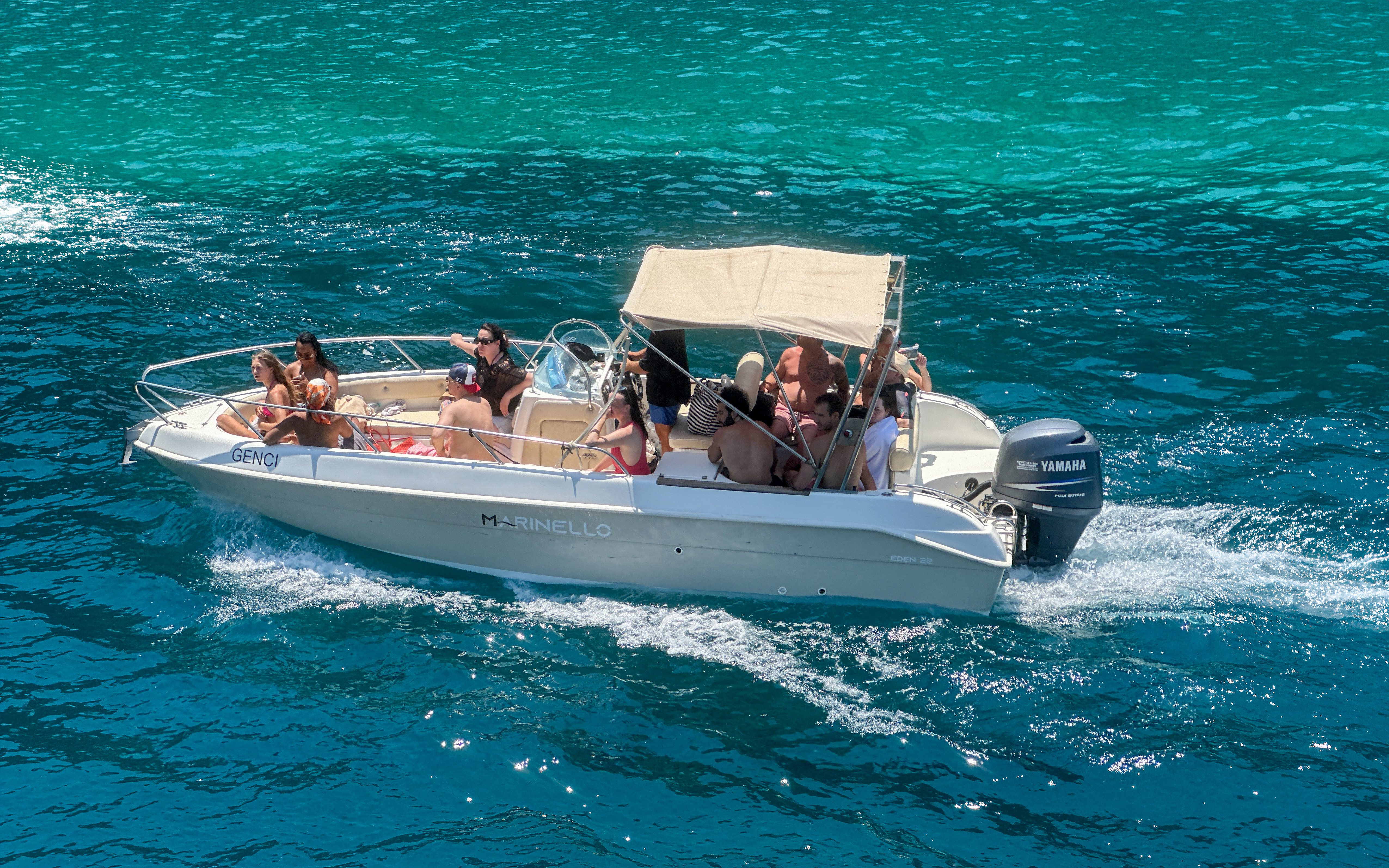 Boat with tourists exploring Ionian Coast hidden beaches and caves.