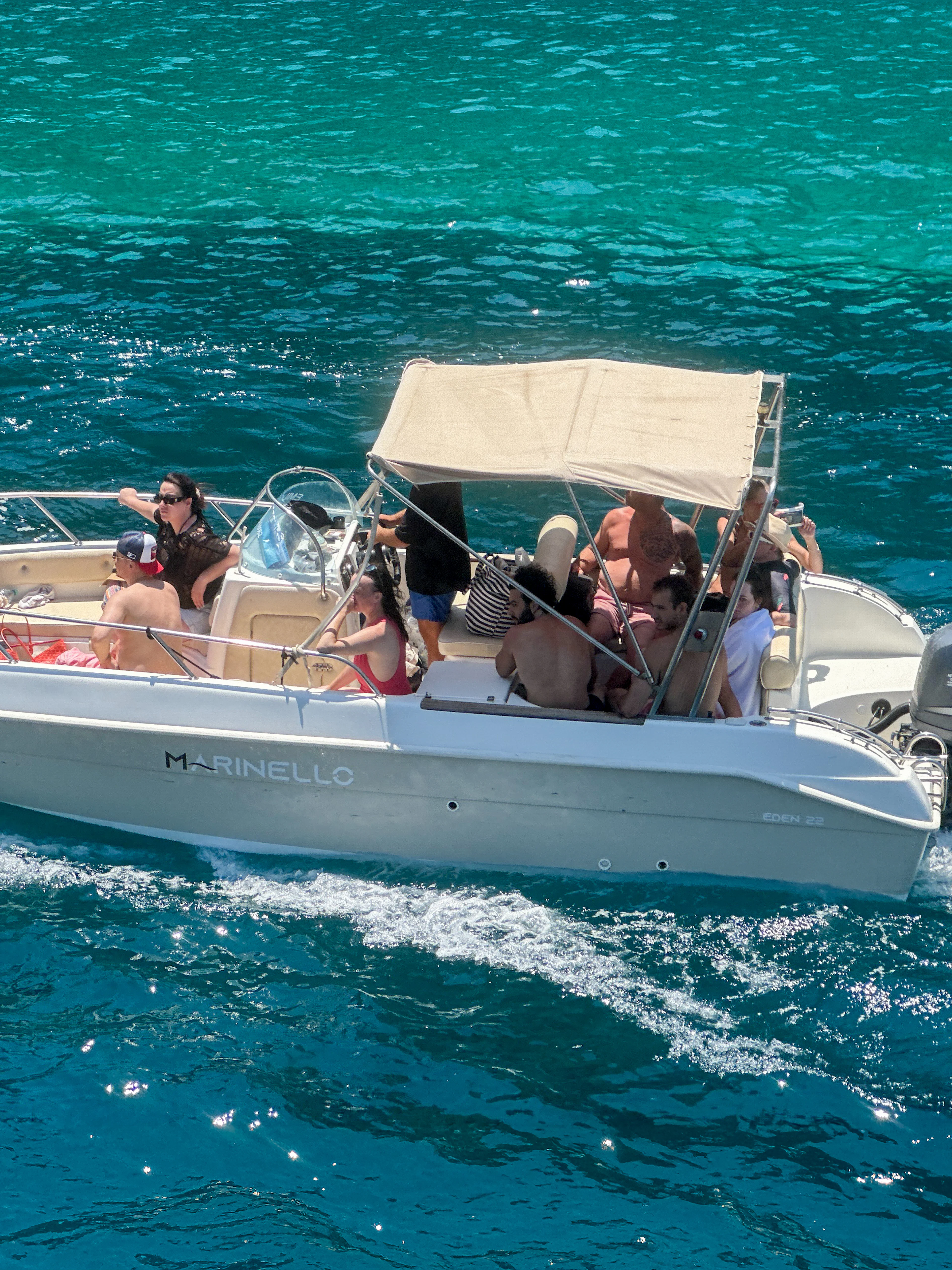 Boat with tourists exploring Ionian Coast hidden beaches and caves.