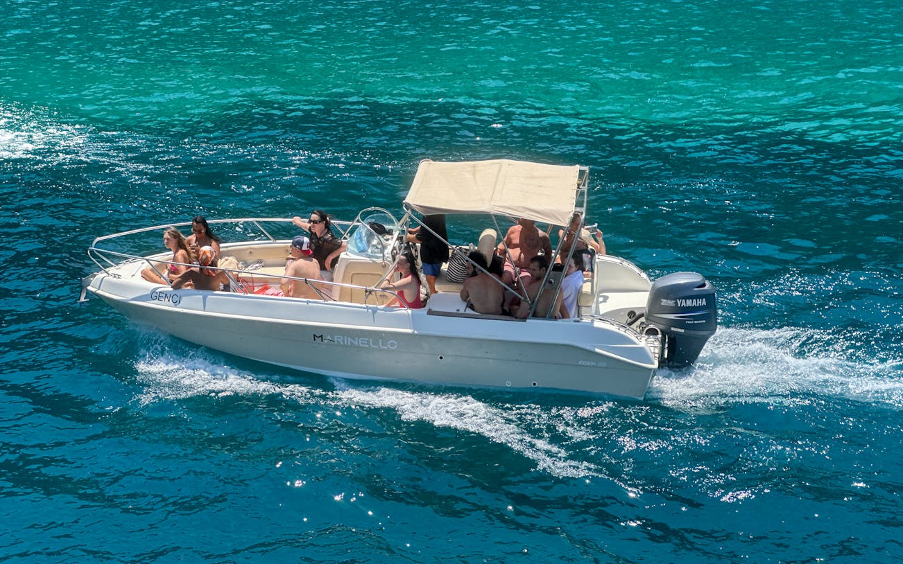 Boat with tourists exploring Ionian Coast hidden beaches and caves.