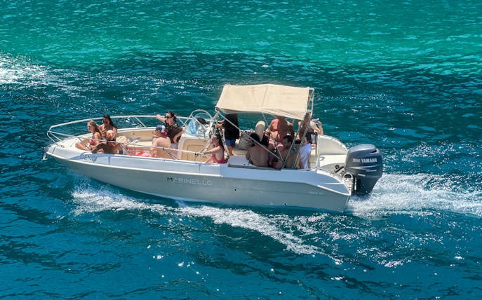 Boat with tourists exploring Ionian Coast hidden beaches and caves.