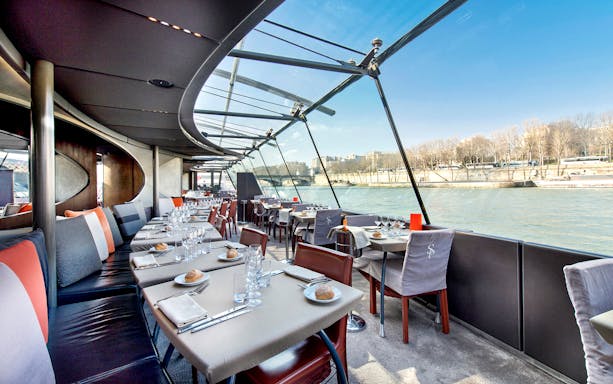 Dining tables set for a Christmas cruise on the Seine River in Paris, starting at the Eiffel Tower.