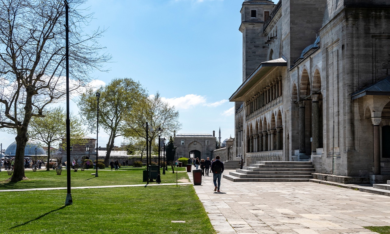 Courtyard of Süleymaniye Mosque with people walking and historic architecture.