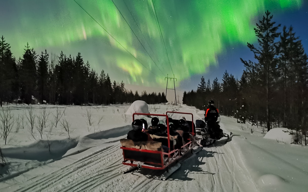 Snowmobile ride under Northern Lights in Levi, Finland.