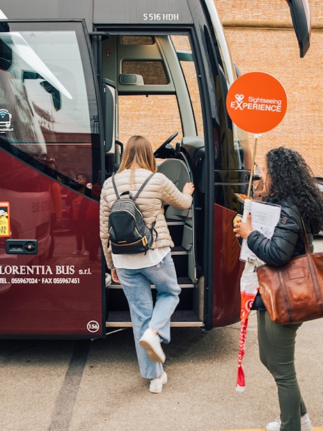 Tourists boarding a bus for the Tuscany in a Day tour, visiting Siena, San Gimignano, and Pisa.