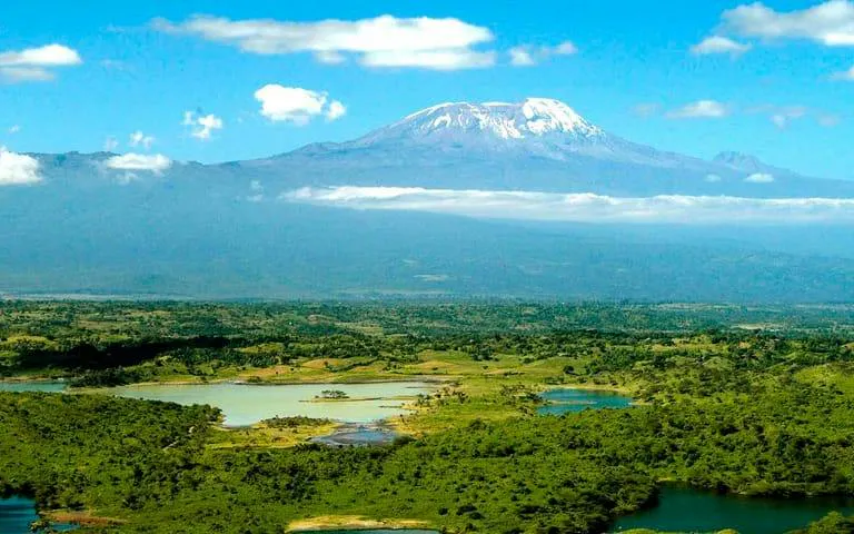 Mount Kilimanjaro view from Arusha National Park, featuring lush greenery and lakes.