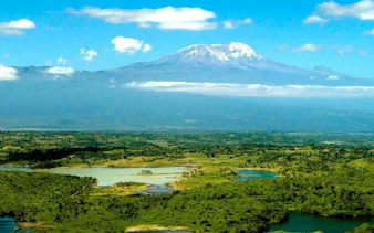 Mount Kilimanjaro view from Arusha National Park, featuring lush greenery and lakes.