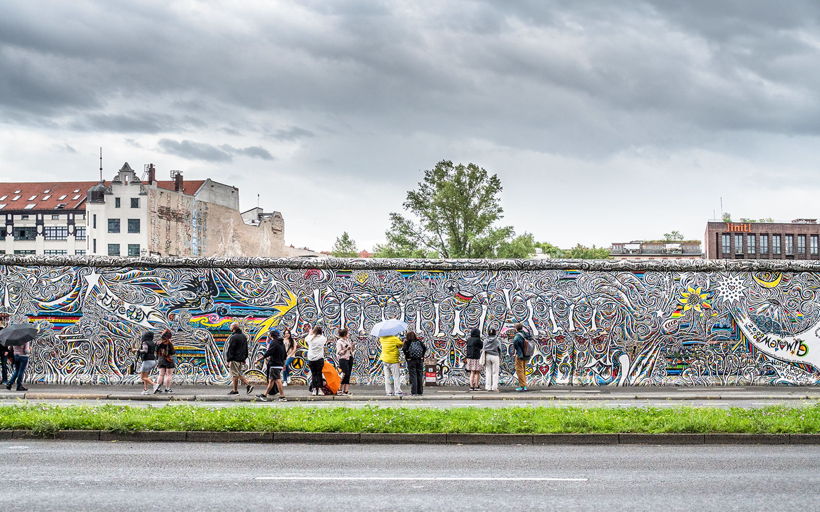 Visitors viewing colorful murals on the Berlin Wall, Germany.