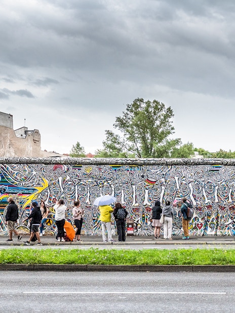 Visitors viewing colorful murals on the Berlin Wall, Germany.
