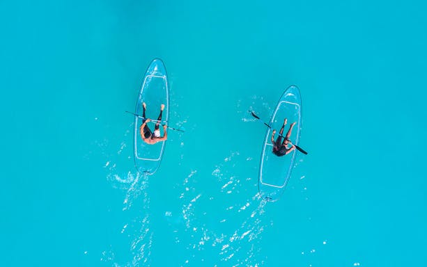 Clear kayaks on turquoise water with Burj Khalifa view in Dubai.