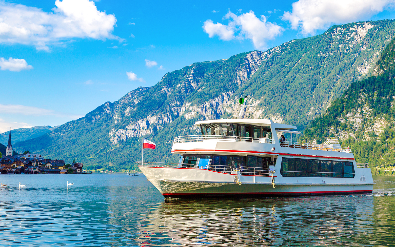 Ship cruising on Hallstatt Lake with mountains in the background, Austria.
