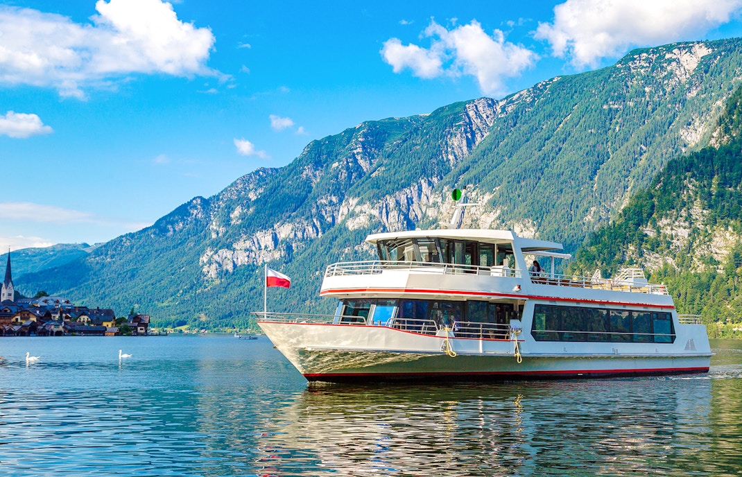 Ship cruising on Hallstatt Lake with mountains in the background, Austria.