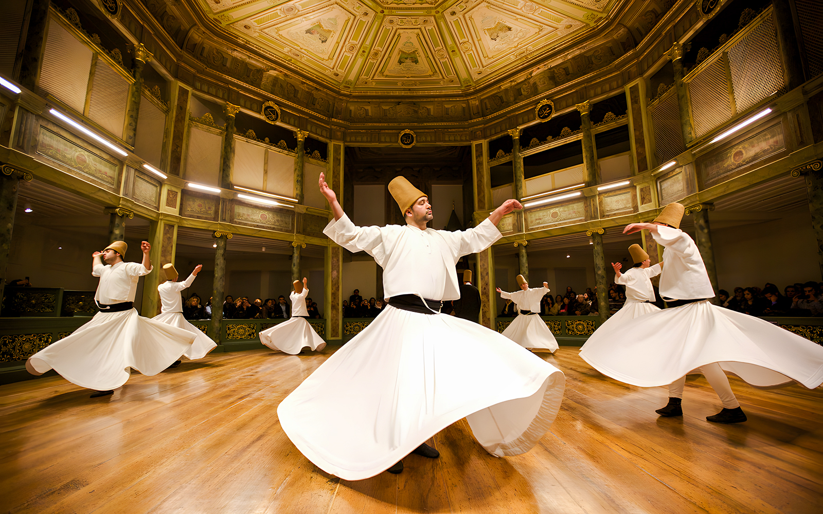 Dervishes performing traditional dance in ornate hall during Dervish Experience.