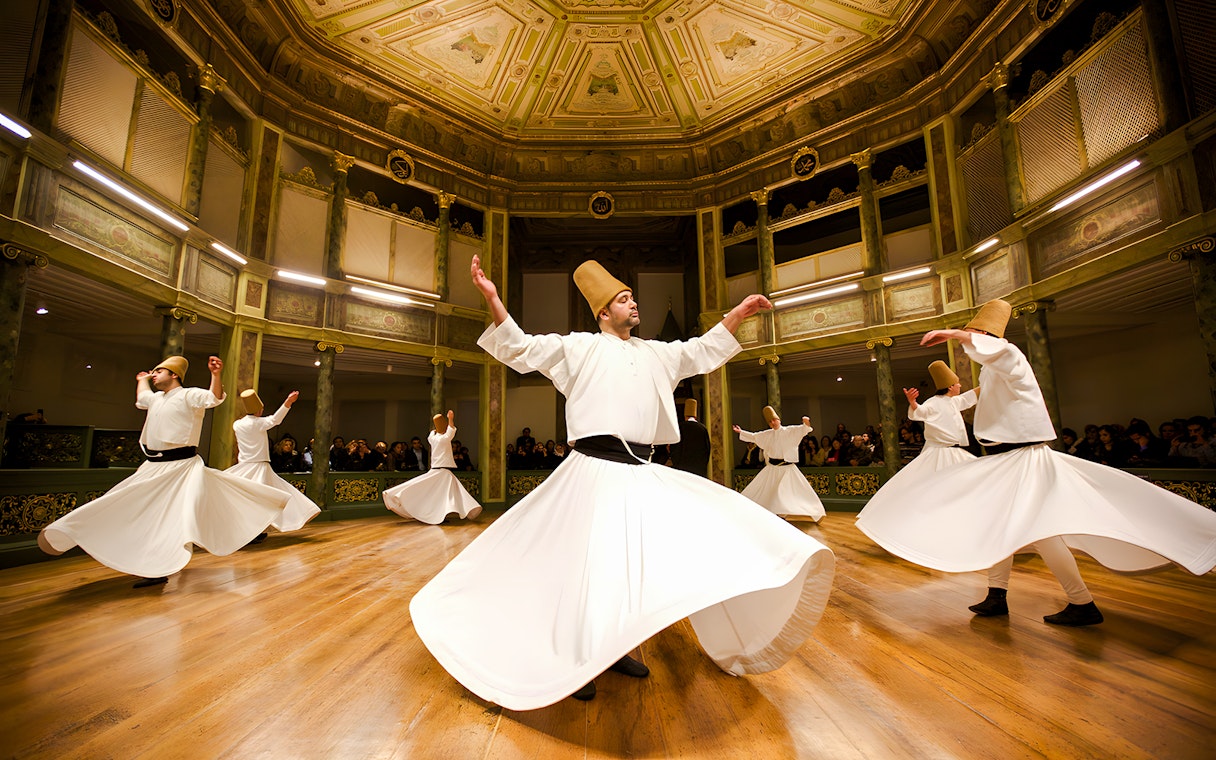 Dervishes performing traditional dance in ornate hall during Dervish Experience.