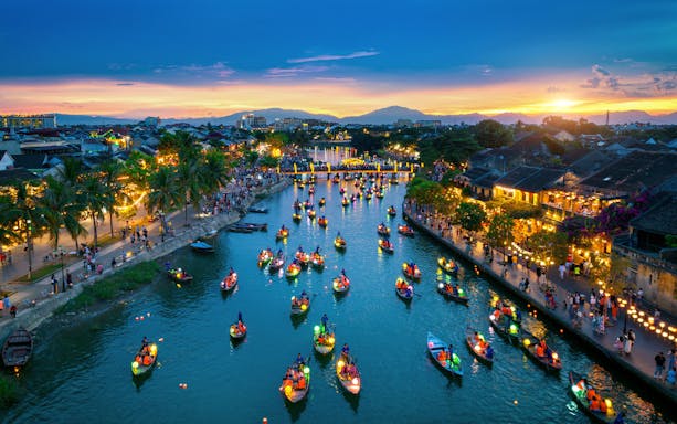 Hoi An ancient town at twilight with lantern-lit streets and traditional Vietnamese architecture.