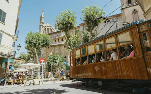 Vintage wooden Sóller tram passing through town square in Mallorca, Spain.