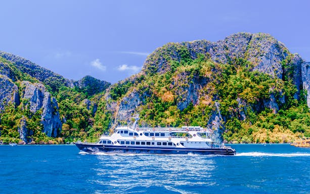 Cruise ship sailing on the Andaman Sea with limestone cliffs in the background.