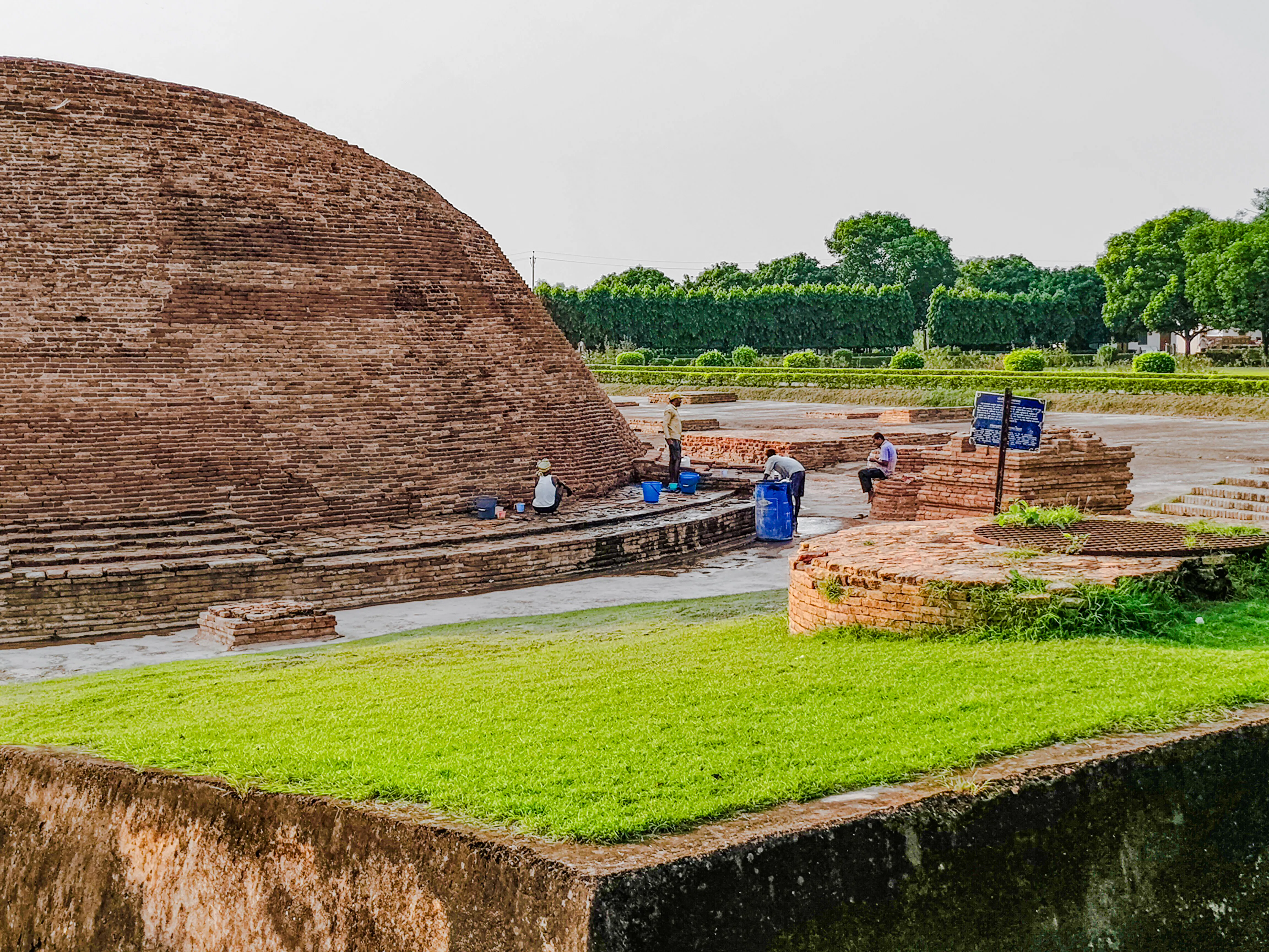 Ancient brick structure with workers at Varanasi archaeological site, India.
