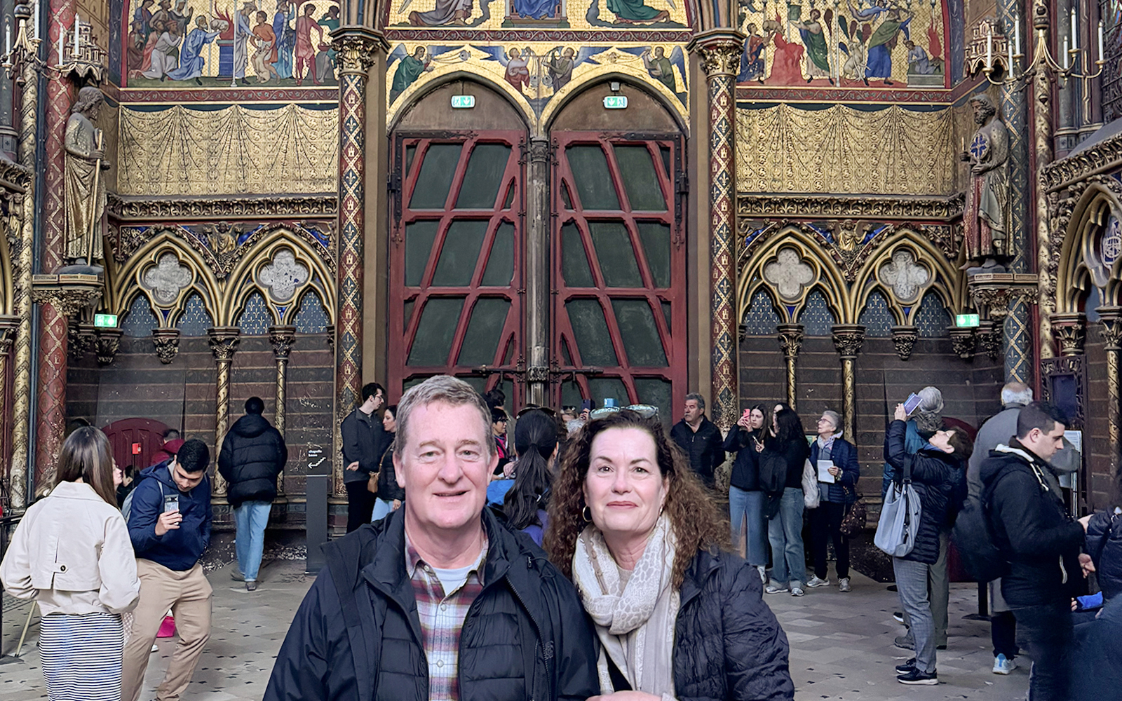 Visitors inside Sainte Chapelle, Paris, admiring the ornate interior and stained glass.