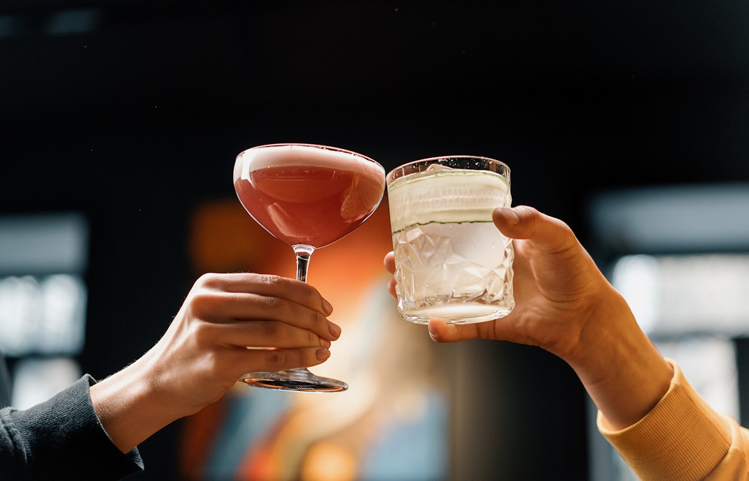 Two people clinking cocktail glasses at a rooftop bar in New York City.