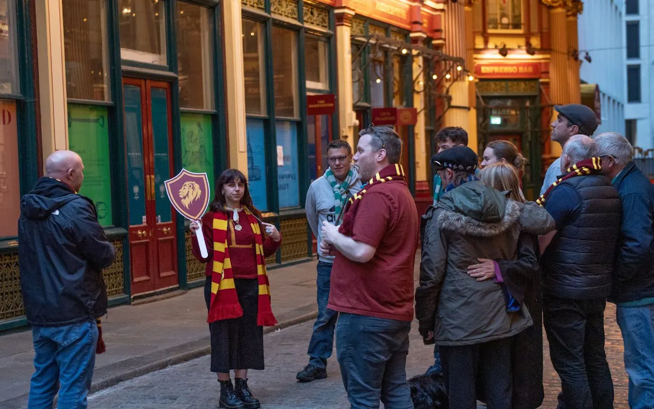 Tour group in London exploring Harry Potter film locations with guide holding Gryffindor sign.