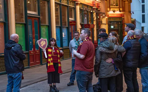 Tour group in London exploring Harry Potter film locations with guide holding Gryffindor sign.