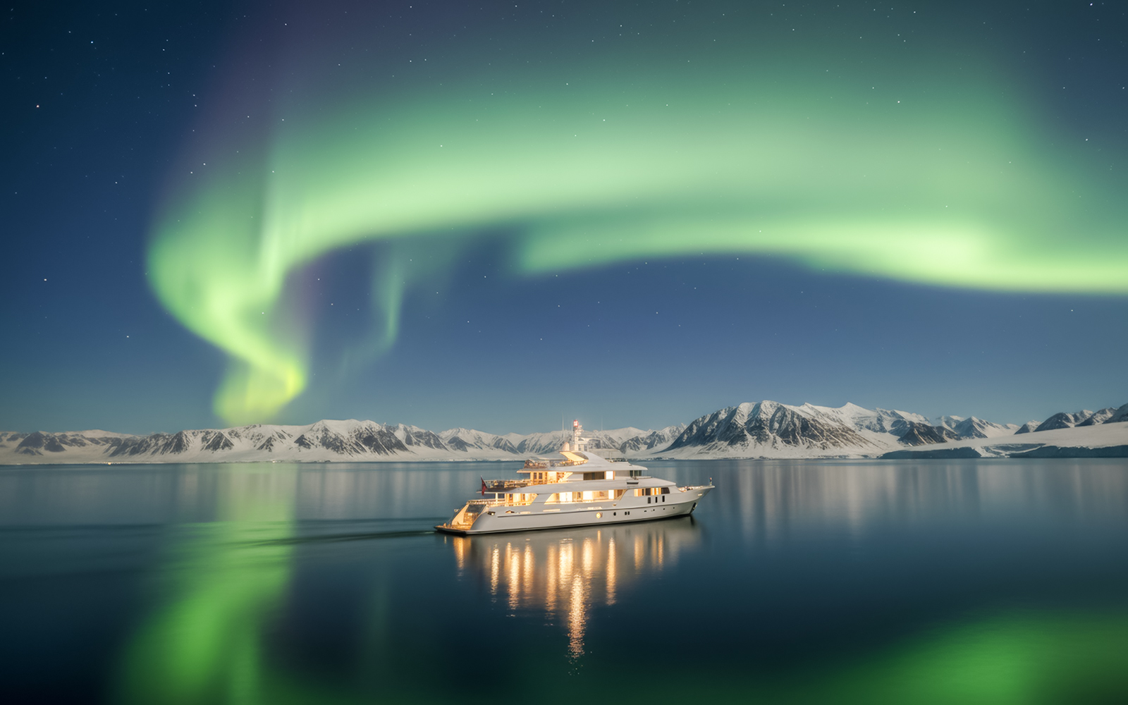 Yacht cruising under Northern Lights with snowy mountains in the background.