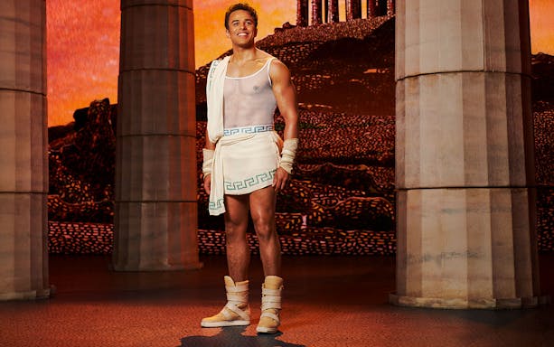Man in ancient Greek attire stands between columns, representing Disney's Hercules.
