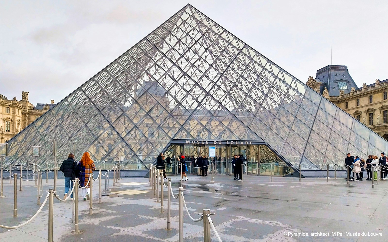 Tourists exploring the pyramid at the Louvre Museum in Paris, France