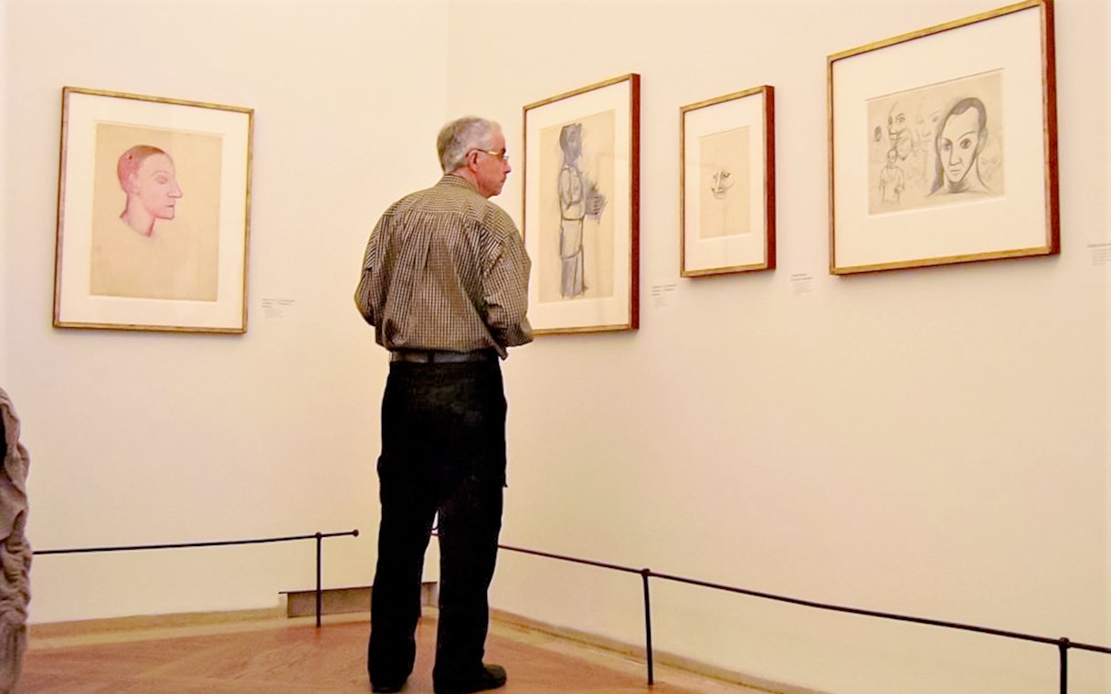 Man observing Picasso sketches at Picasso Museum.