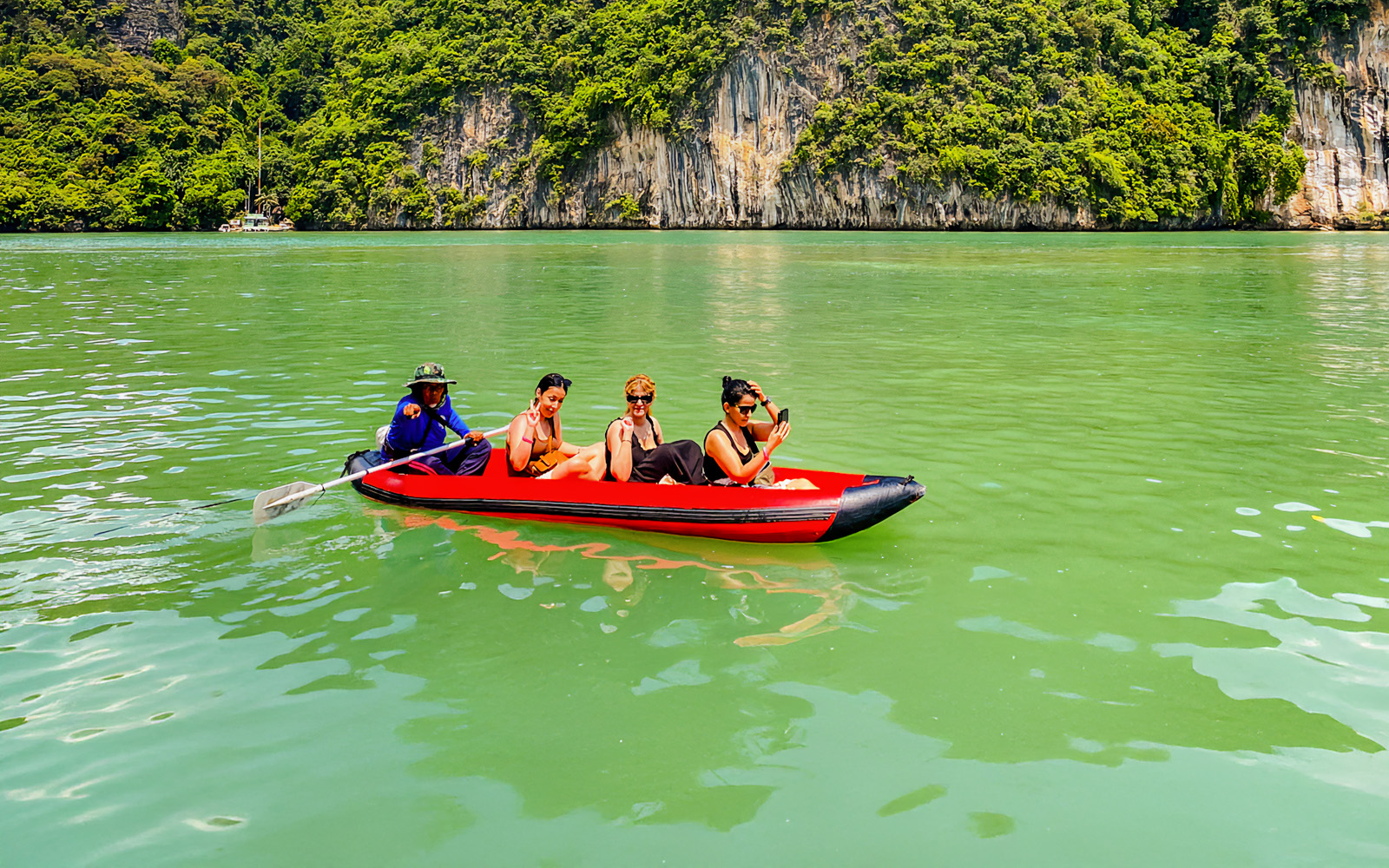Tourists kayaking in Phang Nga Bay with limestone cliffs in the background.