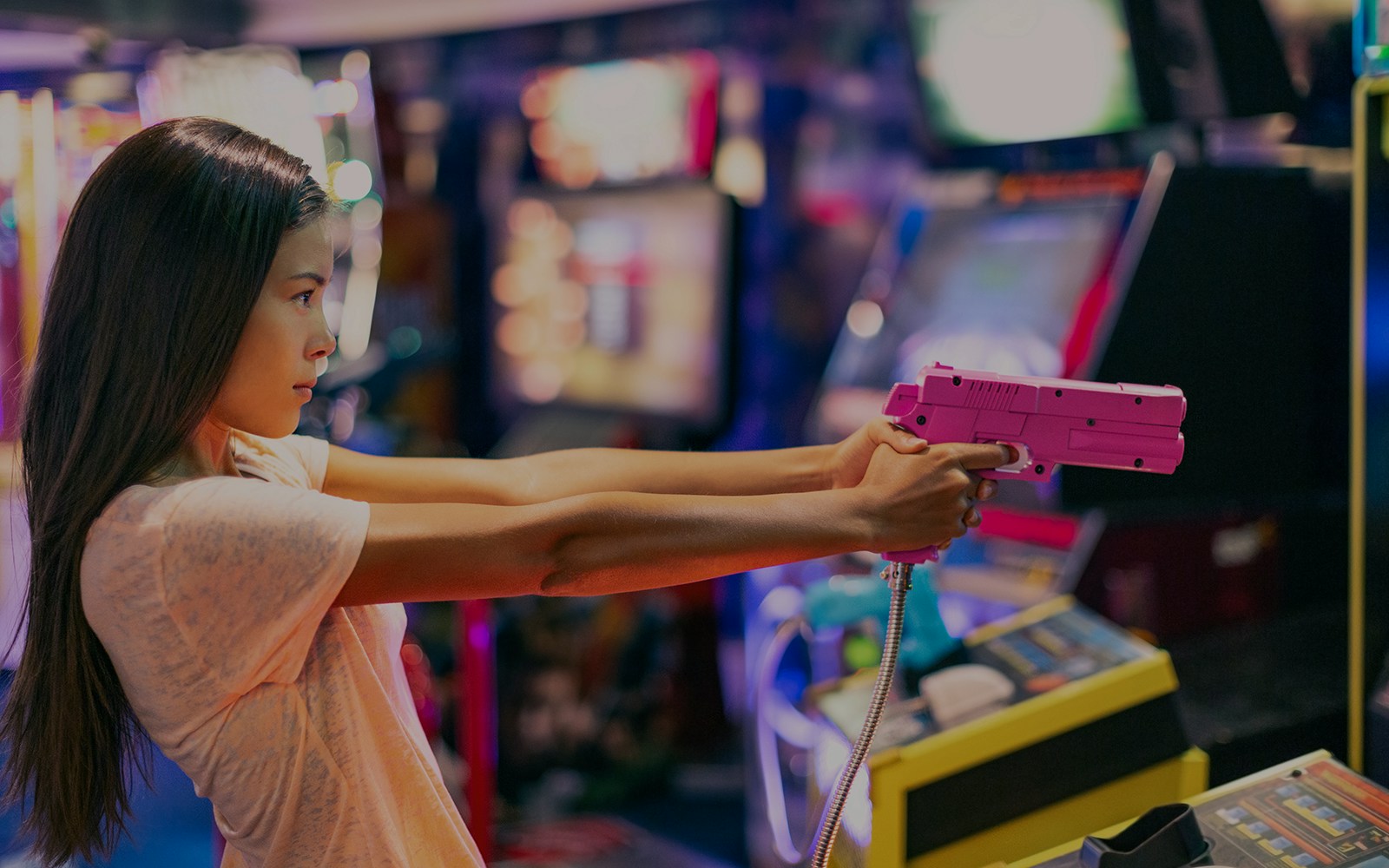Girl playing shooting game in Akihabara arcade, Tokyo.