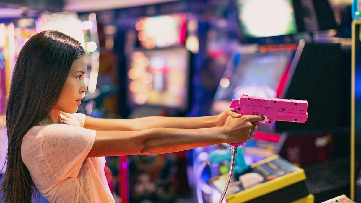 Girl playing shooting game in Akihabara arcade, Tokyo.