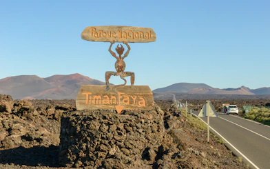 Sign for Timanfaya National Park on a volcanic landscape road in Lanzarote.