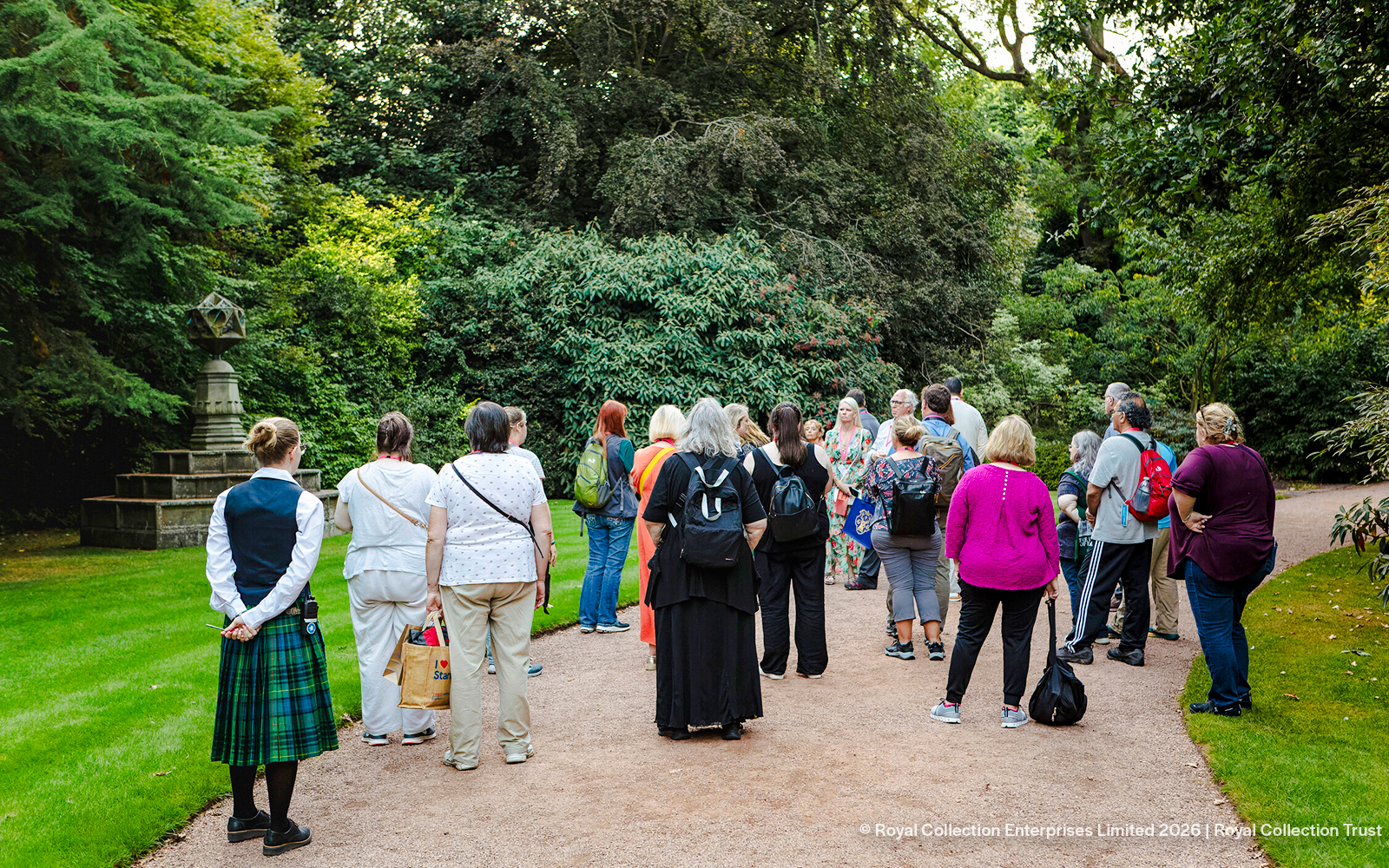 Group of tourists on a guided tour in the gardens of Palace of Holyroodhouse.