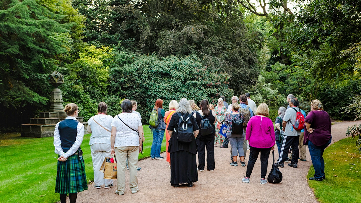 Group of tourists on a guided tour in the gardens of Palace of Holyroodhouse.