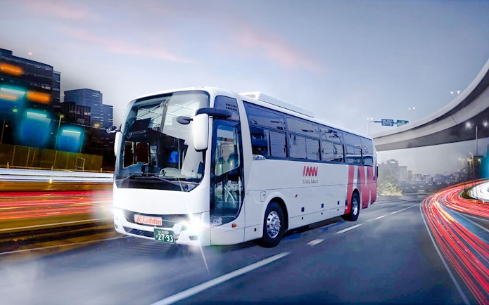 Kansai Airport shuttle van on evening highway with city lights.