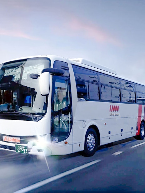Kansai Airport shuttle van on evening highway with city lights.