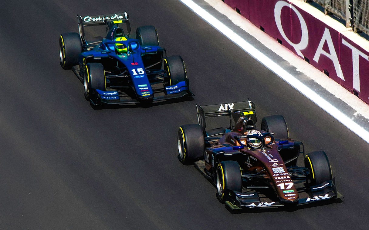 Two Formula 1 cars racing on a track in Qatar.