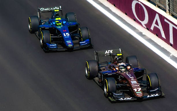 Two Formula 1 cars racing on a track in Qatar.